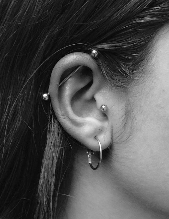 a stylish look with three piercings - a lobe, a tragus and an industrial one, all done with similar accessories