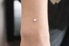 a wrist accented with a large dermal piercing is a bold and shiny idea that you don’t expect to see