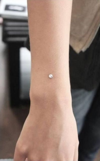 a wrist accented with a large dermal piercing is a bold and shiny idea that you don't expect to see