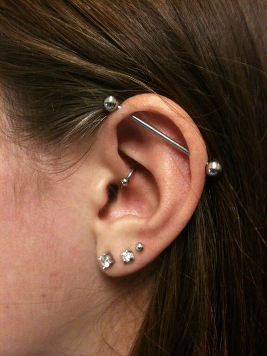 an elegant look with three lobe piercings, a daith one and an industrial one done in silver and with rhinestones