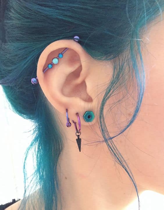 three lobe piercings and a vertical industrial one all done with turquouse and purple earrings and a bar