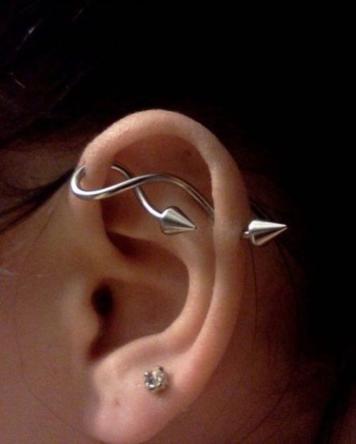 two lobe piercings and a single horizontal industrial one done with a curvy and wavy arrow