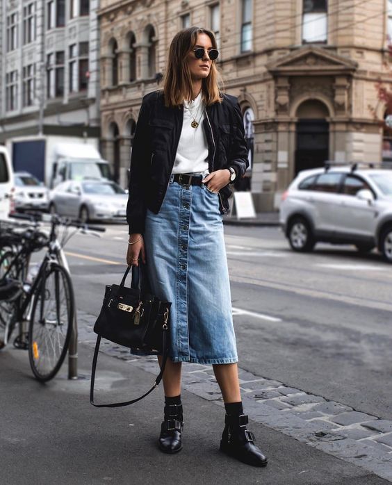 a chic fall outfit with a white tee, a blue denim midi skirt with buttons, a blakc belt, black boots and a black bomber jacket