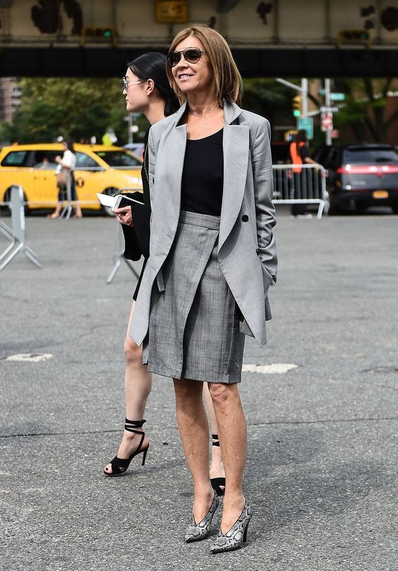 a stylish office look with a black top, a grey oversized blazer, a grey printed skirt, snake print shoes