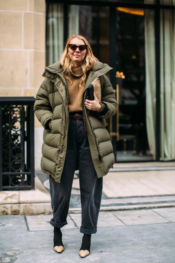 a trendy outfit with a camel turtleneck, blakc shaggy jeans, two tone booties and an oversized green padded coat