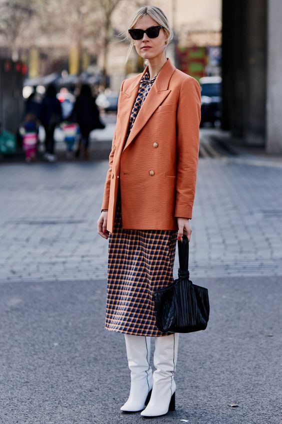 a stylish printed midi dress, a rust-colored oversized blazer, white boots and a black bag for a retro-inspired look
