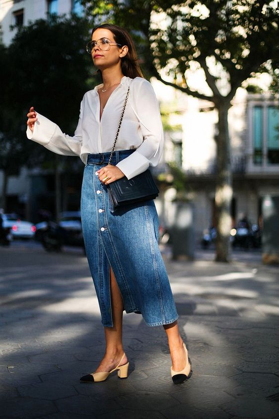 a romantic outfit with a white blouse, a blue denim midi on buttons, two tone shoes and a black bag