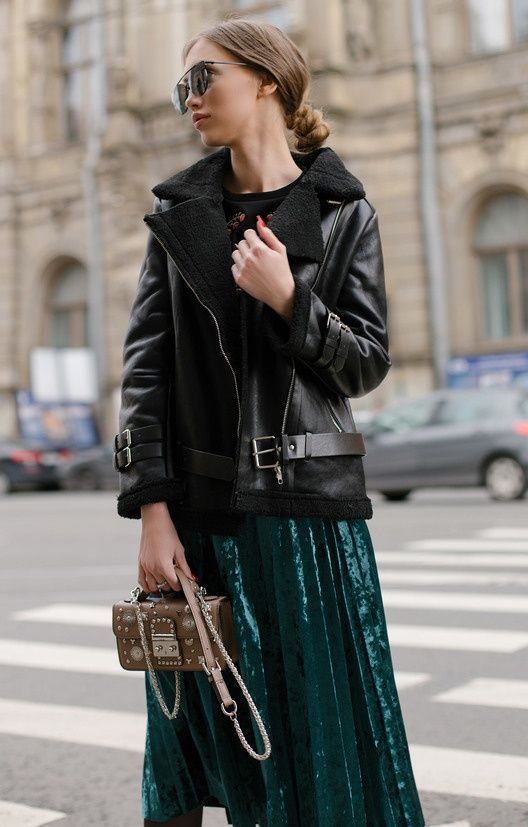 a black sweater, an emerald pleated midi skirt and a black aviator coat plus a whimsy studded bag