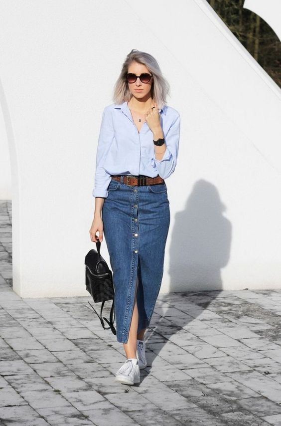 a stylish outfit with a blue shirt, a maxi denim skirt with buttons, a brown leather belt, sneakers and a backpack