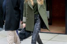 26 Gigi Hadid wearing black leather pants, a green top, black boots, a grene pea coat and a bag
