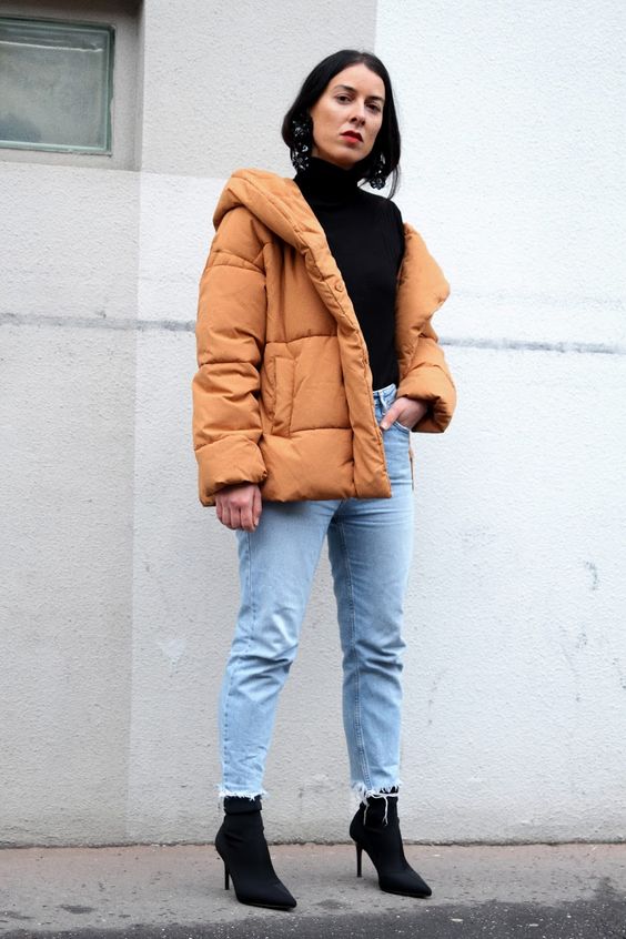 a black turtleneck, blue fringe jeans, blakc sock boots and an amber puffer jacket for a color statement