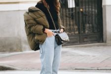 a bold look with a black turtleneck, whitewashed jeans, an olive green cropped puffer jacket and faux fur mules