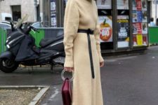 a buttermilk midi knit dress with a turtleneck, long sleeves, a black sash, a burgundy bag and purple boots