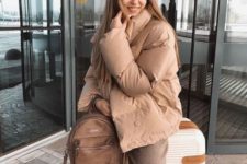 a camel outfit with pants, short puffer jacket, a brown leather backpack for a comfy travel look