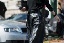 a chic total black look with black leather culottes, black booties with belts, a black jumper and a clutch