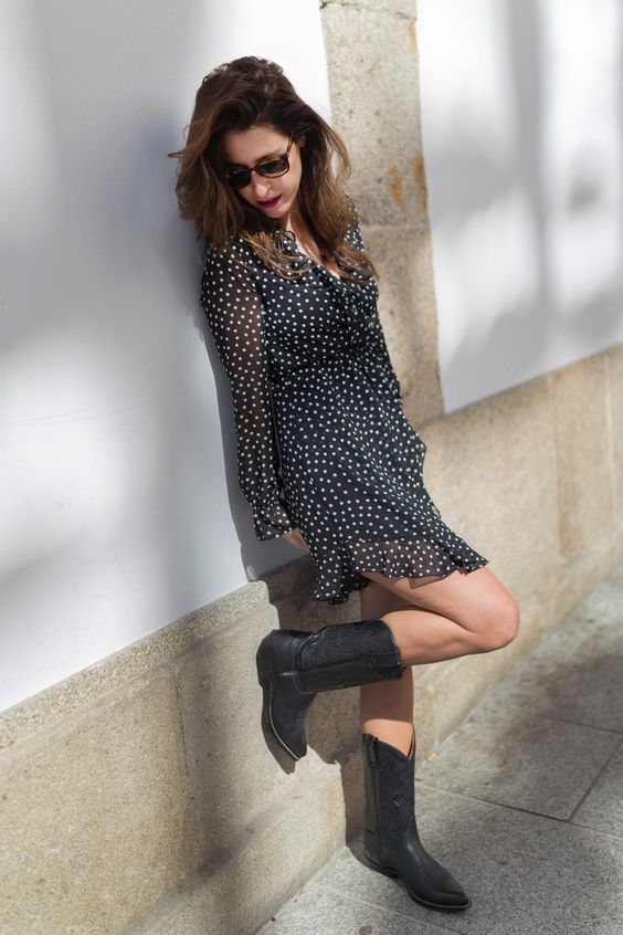 a cute black and white polka dot mini dress with ruffles and long sleeves and black cowboy boots