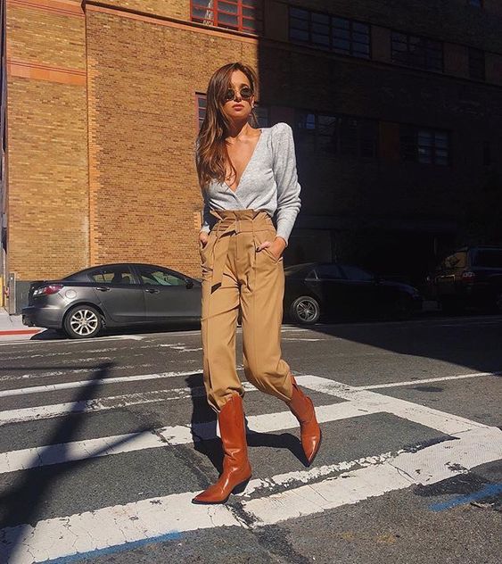 a daring look with a grey blouse, beige high waisted pants tucked into rust-colored cowboy boots