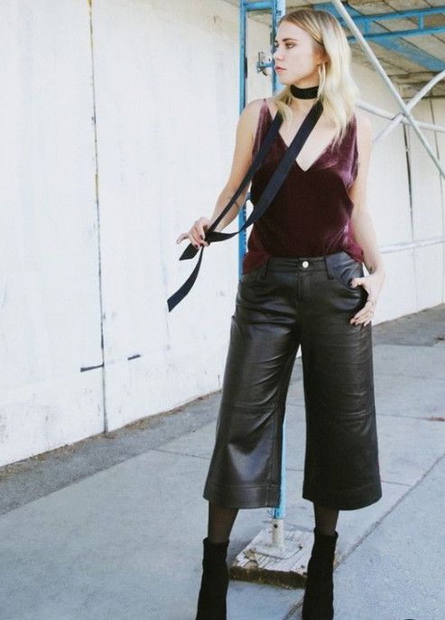 a grunge look with a purple velvet top, black leather culottes, tights, black booties and a choker