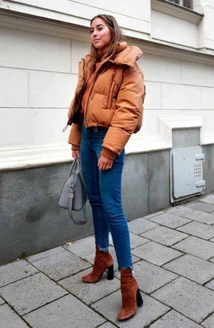 an amber puffer jacket, blue skinny jeans with a raw hem, rust-colored sock boots and a grey bag