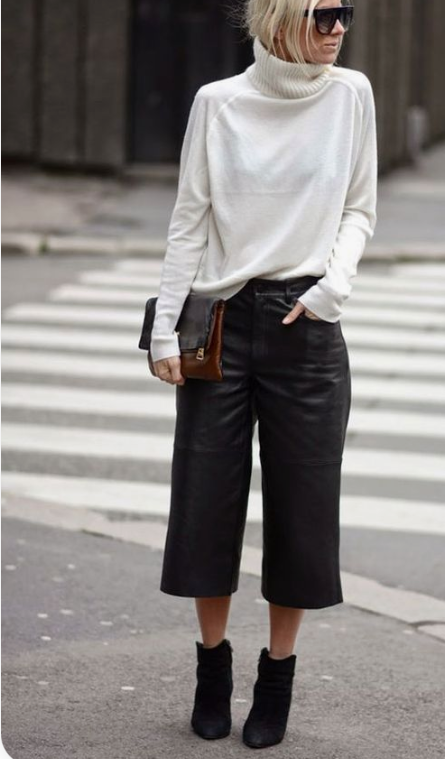 an oversized white cashmere sweater, black leather culottes, black suede booties and a two tone clutch