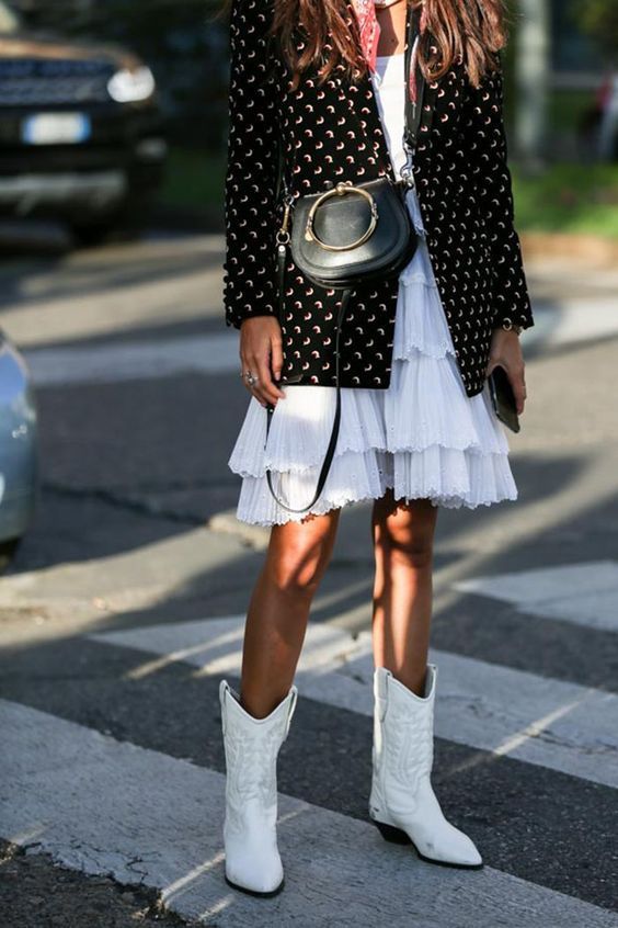 white embroidered cowboy boots, a white ruffled knee dress, a black printed blazer and a black bag