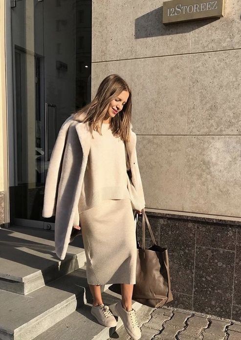a minimalist look with a grey knit suit with a midi skirt, white sneakers and a grey coat plus a brown tote