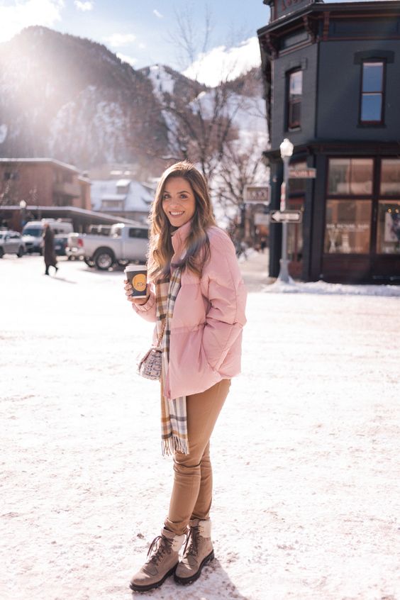 a pink puff jacket, a plaid scarf, tan jeans and beige hiking boots for a glam winter look