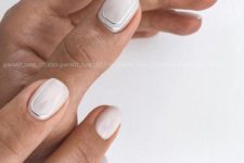 14 glossy white nails with silver stripes along two nails are a chic and refined idea