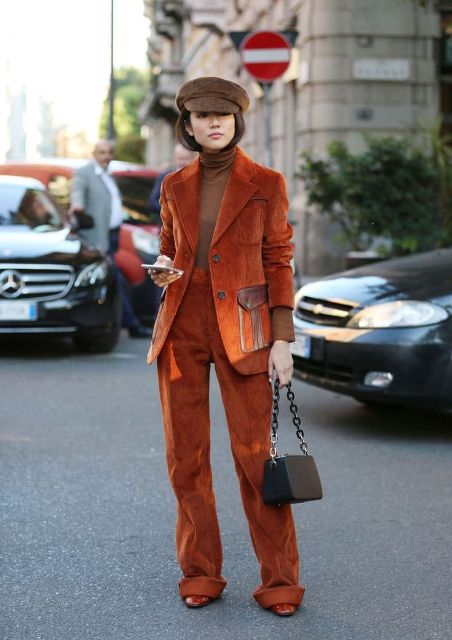 With beige turtleneck, orange suede suit, brown cap and brown boots