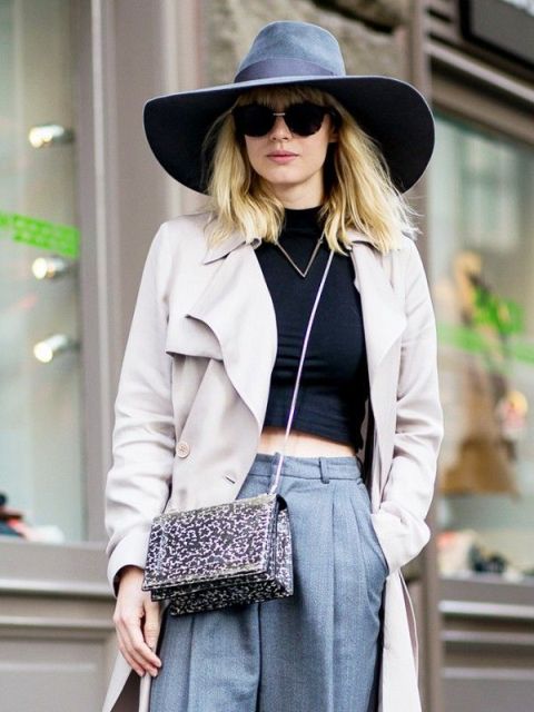 With black crop top, wide brim hat, gray trousers and beige trench coat