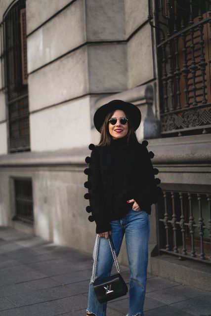 With black wide brim hat, pom pom sweater and jeans