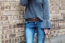 With gray sweater, distressed jeans, high boots and belt