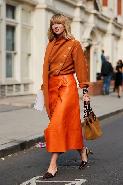 With orange loose sweater, orange leather midi skirt and low heeled shoes