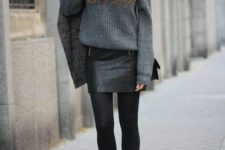 a grey oversized sweater, a black leather mini skirt, black tights and booties, a plaid coat