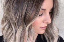 a medium length haircut with waves and a slight mushroom blond balayage plus a darker root for a trendy touch