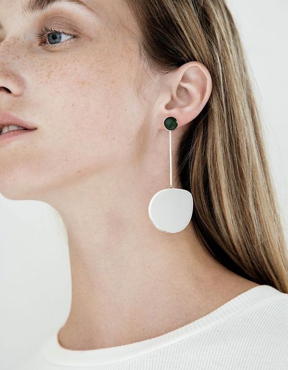 a statement minimalist earring of a black bead and an asymmetrical white stone