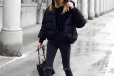 a total black look with a tee, ripped jeans, a cropped puffer jacket, white sneakers and socks