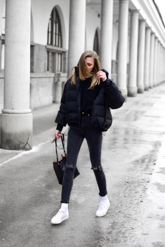a total black look with a tee, ripped jeans, a cropped puffer jacket, white sneakers and socks