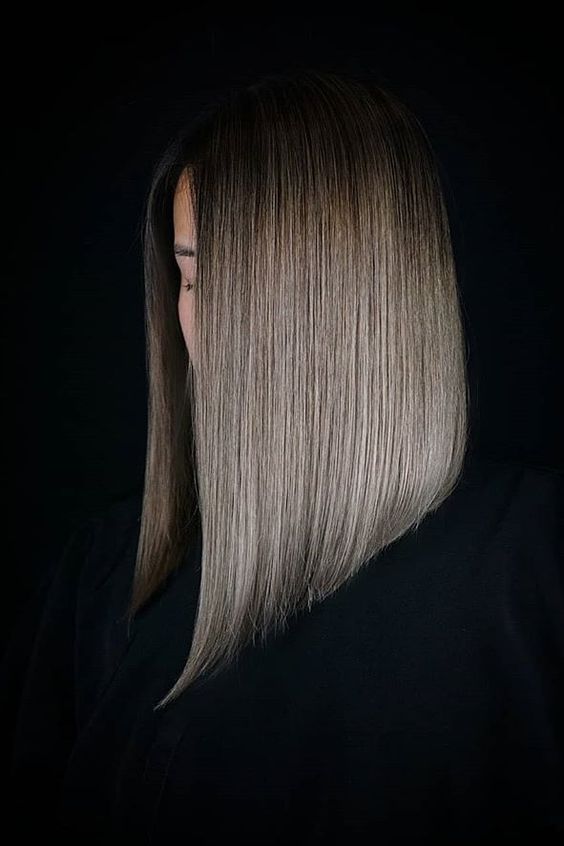 an asymmetrical long bob on straight hair and done in mushroom blond with a slight darker root for a modern feel