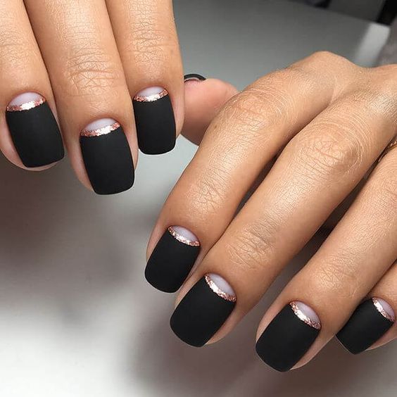 an elegant matte black manicure with shiny copper lines and moon detailing