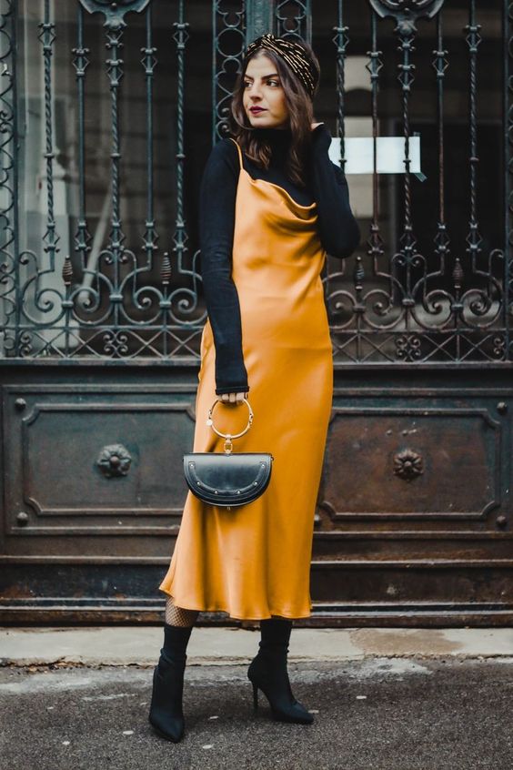 black sock boots, a blakc turtleneck, a marigold slip midi dress and a black bag on a ring for a refined feminine look