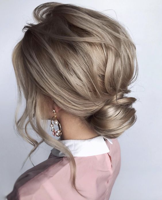 mushroom blond hair with waves made into a low bun with a messy top is a chic idea for every day