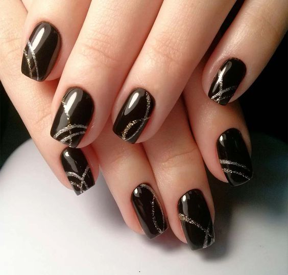 shiny black naiils with gold glitter stripes is a very creative and chic idea for a NYE party
