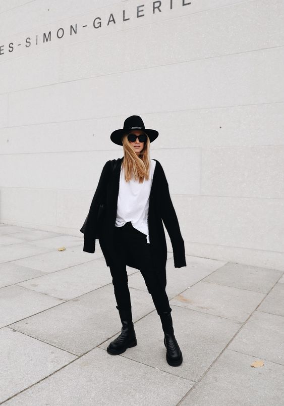 a relaxed monochromatic look with a white tee, black jeans, black chunky boots, a black short coat and a hat