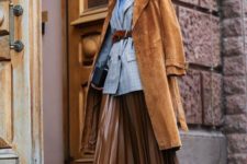 a layered look with a blue top, a grey blazer, a rust-colored trench, a brown leather midi and black boots