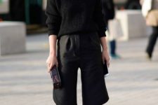 With black sweater, clutch and black culottes