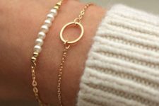 a duo of chic and delicate gold bracelets with pearls and a circle pendant for a girlish look