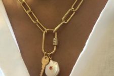 a gold chunky chain necklace with a baroque pearl and a key pendant features two trends – heavy chains and pearls