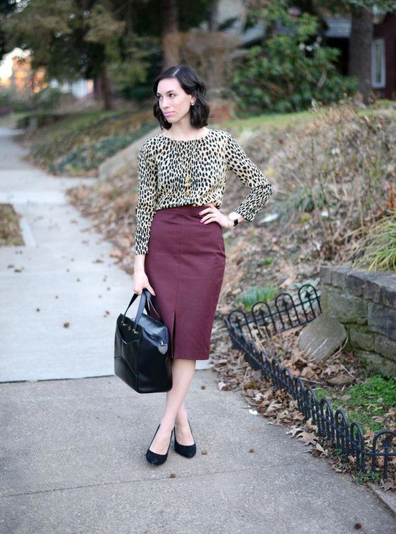 a leopard print top with long sleeves, a high neckline, a burgundy leather midi with a front slit, a black bag and shoes