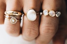 a number of stacked gold rings with moonstones and diamonds that vary in shapes but still match